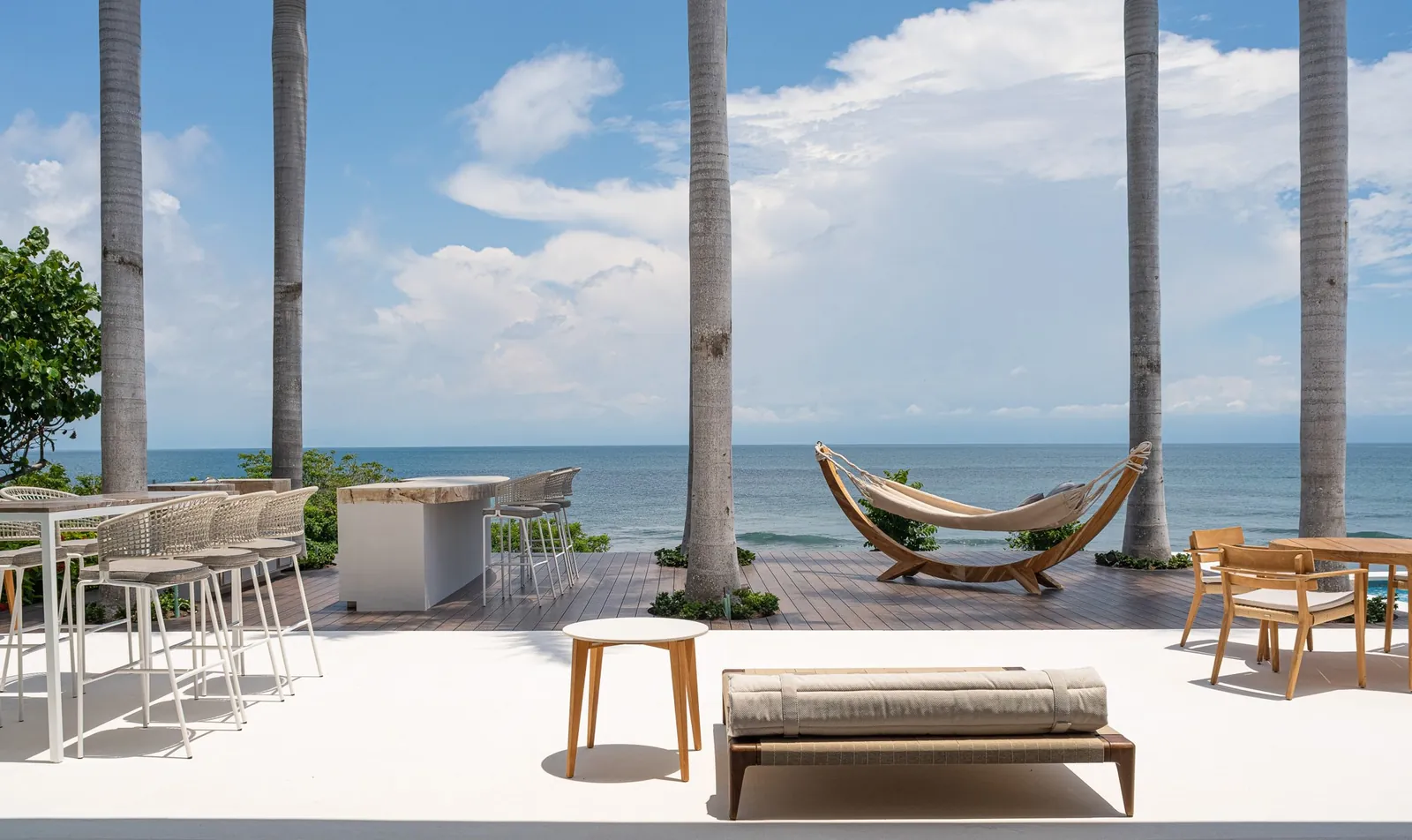 A hammock and bar seating on the oceanfront deck under the palms