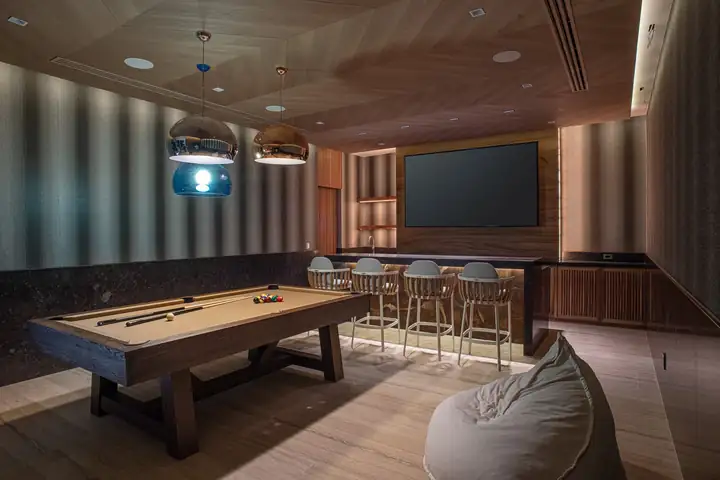 The game room with its pool table, bar stools and big screen