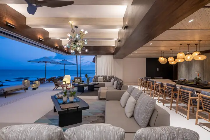 The living room lit at blue hour, the bay outside