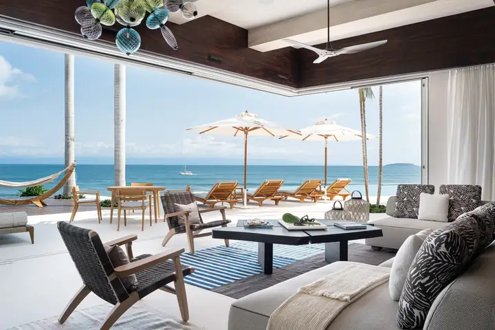 The living room with its glass walls slid open to the terrace and the ocean
