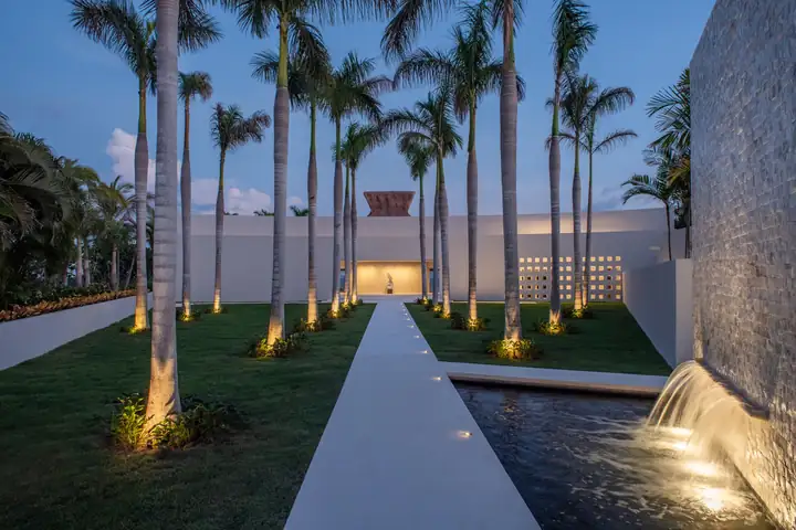 The palm-lined entrance avenue and water feature lit at dusk